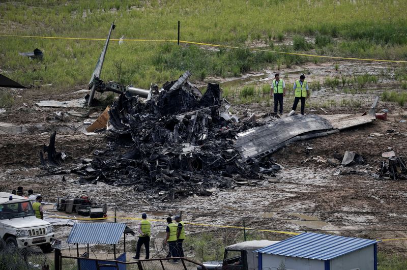 © Reuters. FILE PHOTO: Officials from the airport stand near the wreckage of a Saurya Airlines plane that caught fire after skidding off the runway while taking off at Tribhuvan International Airport, in Kathmandu, Nepal, July 24, 2024. REUTERS/Navesh Chitrakar/File Photo