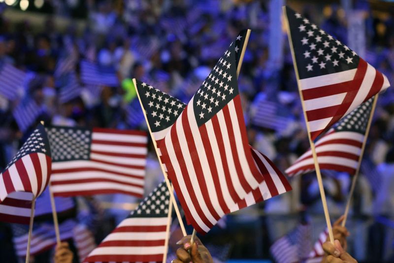 © Reuters. FILE PHOTO: Attendees wave U.S. flags on Day 4 of the Democratic National Convention (DNC) at the United Center in Chicago, Illinois, U.S., August 22, 2024. REUTERS/Alyssa Pointer/File Photo