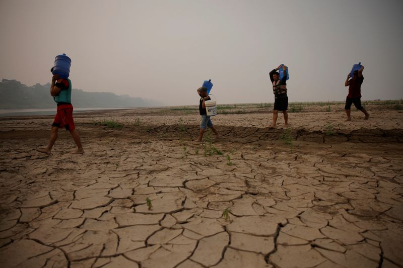 © Reuters. River dwellers carry water gallons, on the sandbanks of the Madeira river, to bring to the isolated region of Paraizinho community, during the worst drought of the river in history, Humaita, Amazonas state, Brazil September 8, 2024. REUTERS/Bruno Kelly