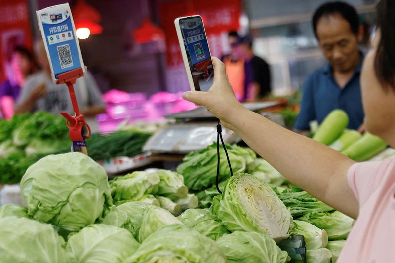 © Reuters. FILE PHOTO: A customer scans a QR code to pay for vegetables at a morning market in Beijing, China August 9, 2023. REUTERS/Tingshu Wang/File Photo