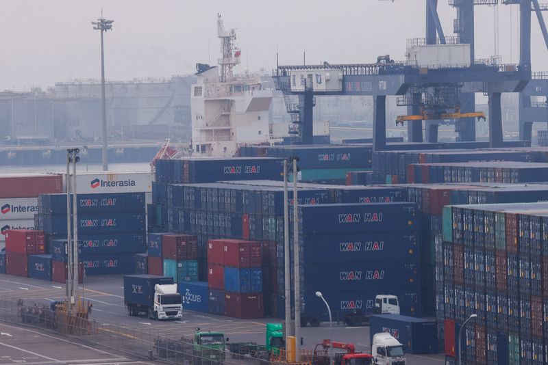 © Reuters. FILE PHOTO: Trucks drive between cargo containers at Port of Taichung in Taichung, Taiwan April 18, 2023. REUTERS/Ann Wang/File Photo