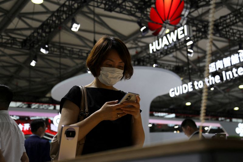 © Reuters. FOTO FILE: Seorang pengunjung memeriksa ponsel di dekat logo Huawei selama Mobile World Congress di Shanghai, Tiongkok, 28 Juni 2023. REUTERS/Nicoco Chan/Foto File