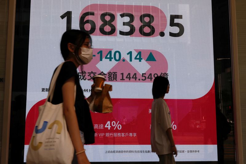 &copy; Reuters. People walk past a panel displaying figures of China stock indexes and Hang Seng Index at the Financial Central district in Hong Kong, China August 6, 2024. REUTERS/Tyrone Siu/file photo