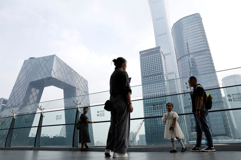 © Reuters. FILE PHOTO: People stand at a shopping mall near the CCTV headquarters and the China Zun skyscraper in the central business district (CBD) of Beijing, China, September 7, 2023. REUTERS/Tingshu Wang/File Photo