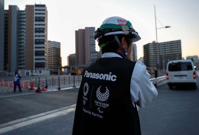 © Reuters. FILE PHOTO: A worker wears a jacket with the logo of Panasonic, Tokyo 2020 Olympic and Paralympic Games' partner, as he walks at an under-construction site of the Olympic villages in Tokyo, Japan March 25, 2020. REUTERS/Issei Kato