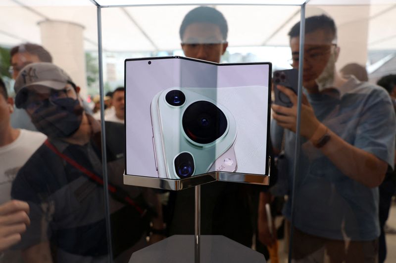 © Reuters. People look at Huawei's new tri-foldable smartphone Mate XT displayed in a glass case at a Huawei flagship store in Beijing, China September 10, 2024. REUTERS/Florence Lo