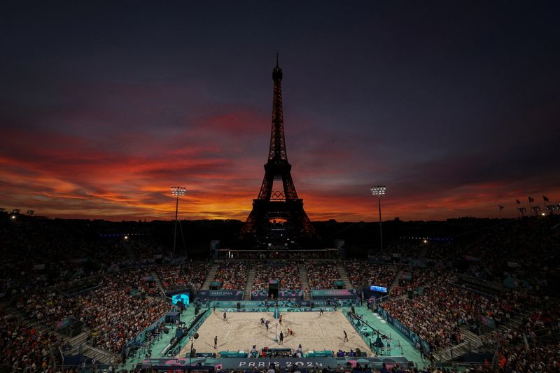 © Reuters. FILE PHOTO: Paris 2024 Olympics - Beach Volleyball - Men's Round of 16 Match - Brazil vs Netherlands (Evandro/Arthur vs van de Velde/Immers) - Eiffel Tower Stadium, Paris, France - August 04, 2024. General view of the Eiffel Tower Stadium shows the Eiffel Tower and the Olympic rings at dusk as the match is on. REUTERS/Paul Childs/File Photo