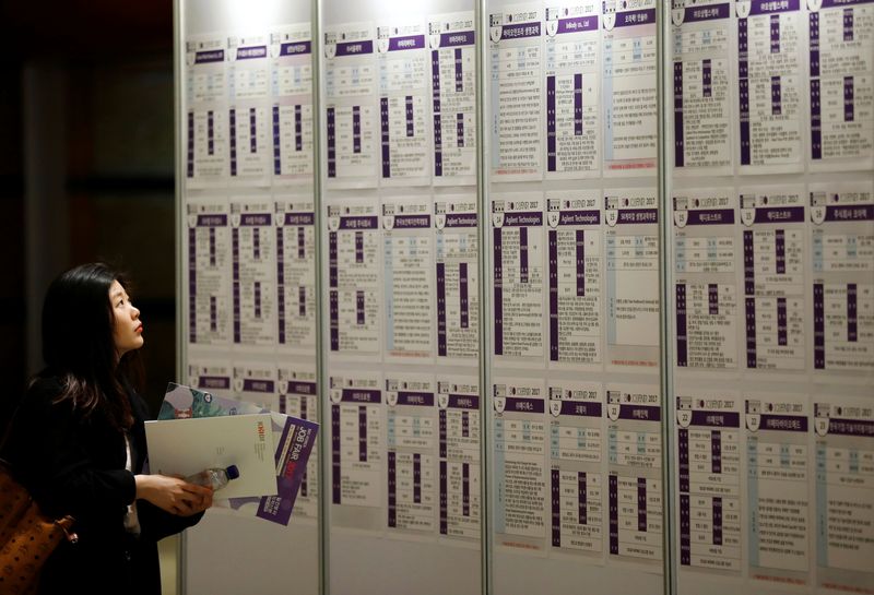 © Reuters. FILE PHOTO: A woman looks at recruiting information during a job fair in Seoul, South Korea, April 12, 2017. REUTERS/Kim Hong-Ji/File Photo