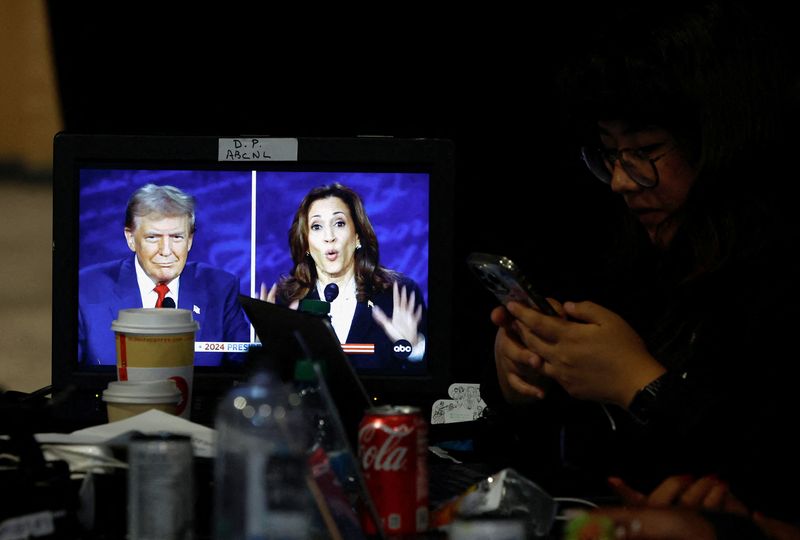 © Reuters. A member of the media uses a screen phone to show the presidential debate as Republican presidential candidate former US President Donald Trump and Democratic presidential candidate US Vice President Kamala Harris attend a presidential debate hosted by ABC in Philadelphia, Pennsylvania, USA, September 10, 2024. REUTERS/Evelyn Hockstein