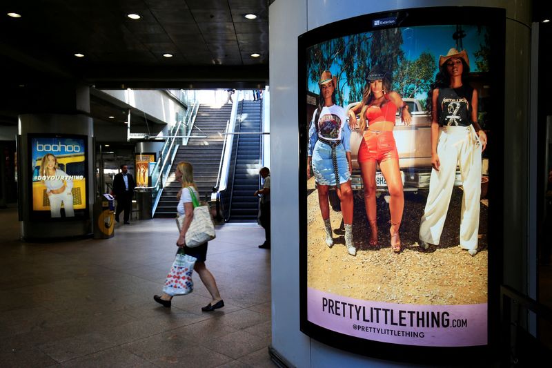 &copy; Reuters. FILE PHOTO: A shopper walks pass advertising billboards for Boohoo and for 'Pretty Little Things', a Boohoo brand, at Canary Wharf DLR station in central London, Britain, September 17, 2018. REUTERS/James Akena/File Photo