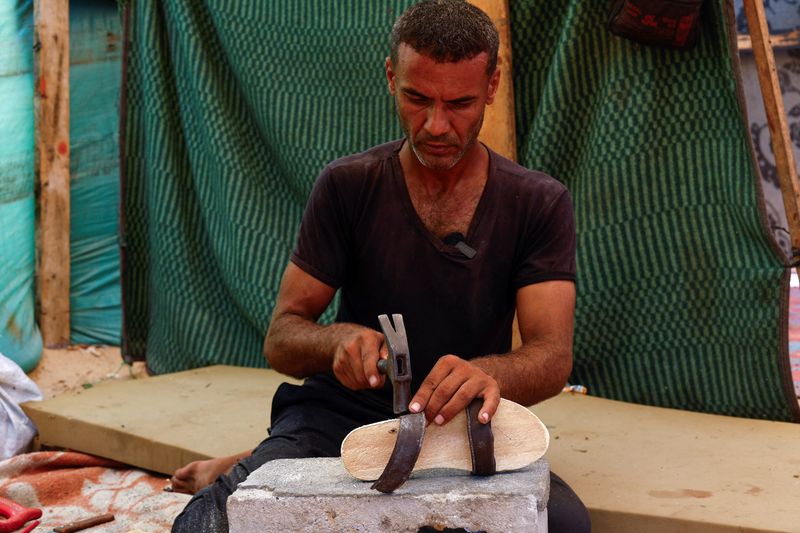 &copy; Reuters. Palestinian Saber Dawas crafts wooden sandals due to a shortage of footwear in the enclave and the lack of financial means to afford those which are available in the market, amid the Israel-Hamas conflict, in Khan Younis in the the southern Gaza Strip, Se