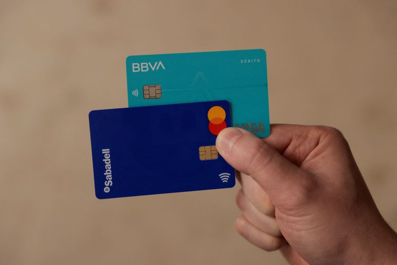 © Reuters. FILE PHOTO: A man shows his debit cards of BBVA and Sabadell banks, in Ronda, Spain, May 9, 2024. REUTERS/Jon Nazca/File Photo