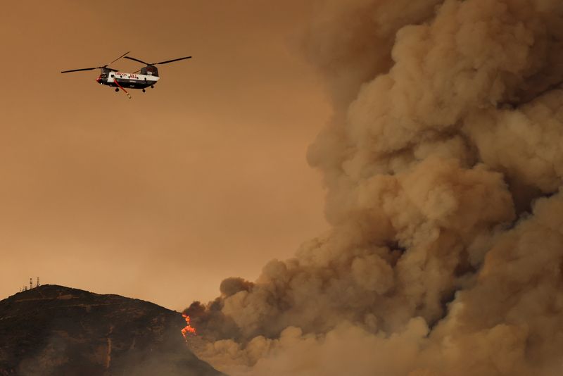 &copy; Reuters. FILE PHOTO: A helicopter flies, as the Airport Fire burns in the hills of Orange County, California, U.S., September 9, 2024.  REUTERS/Mike Blake/File Photo