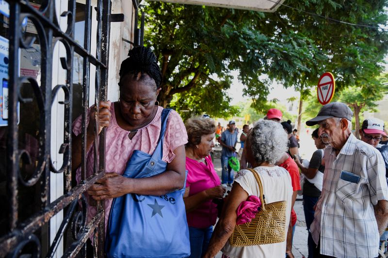 &copy; Reuters. Mulher se segura em uma cerca ao sair de um comércio em Havana enquanto outras pessoas esperam para entrarn04/09/2024nREUTERS/Norlys Perez