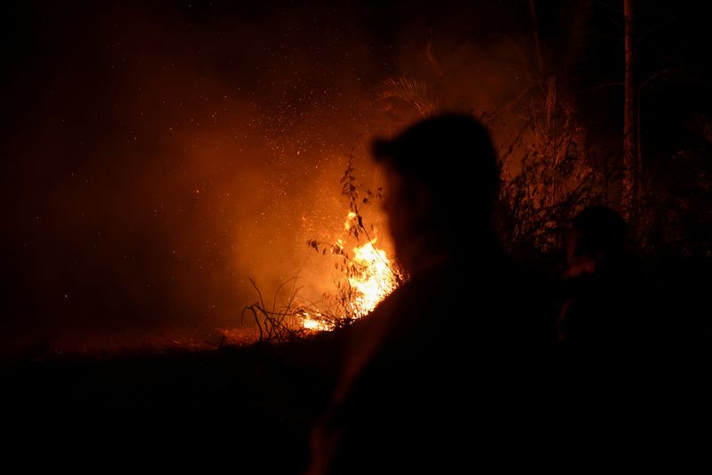 ©Reuters. FILE PHOTO: Fire rises near members of the armed forces as Bolivia this year records the most outbreaks of forest fires since 2010, affecting about 3 million hectares (7.5 million acres) of land in Bolivia's Nuflo de Chavez province, according to experts is set on fire, on August 25, 2024. REUTERS/Claudia Morales/File Photo