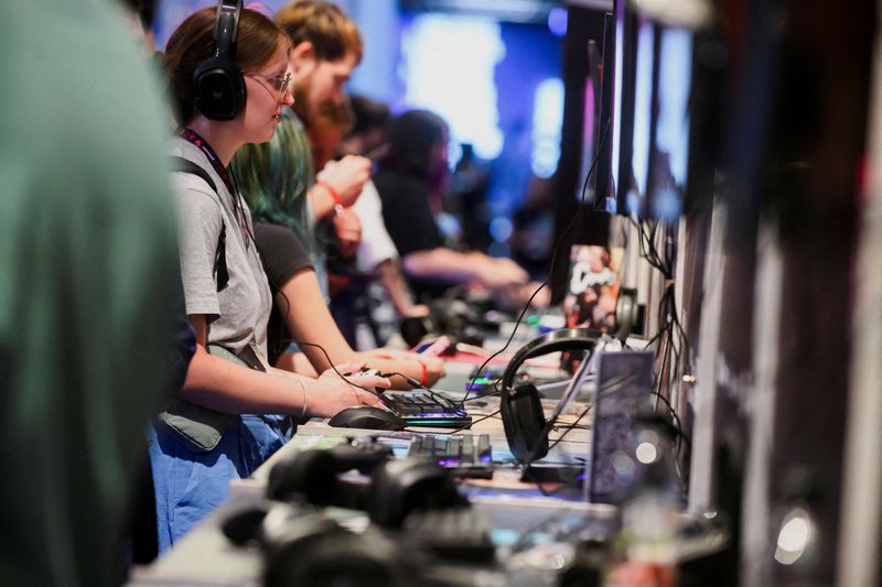 © Reuters. FILE PHOTO: Visitors play a game during the 2024 Gamescom computer and video game industry event in Cologne, Germany, August 21, 2024. REUTERS/Jana Rodenbusch/File Photo