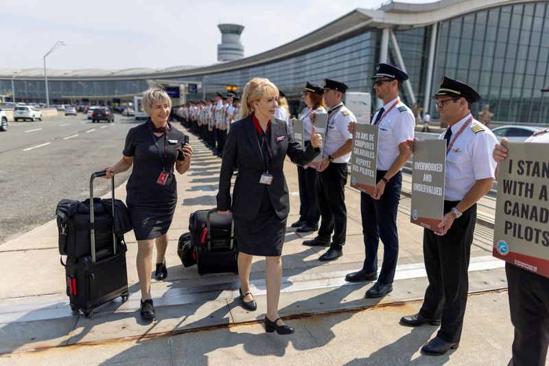 © Reuters. FILE PHOTO: A member of the Air Canada crew gives a thumbs up to pilots represented by the Air Line Pilots Association, Int’l (ALPA), who voted to authorize a strike, as they hold an informational picket at Toronto Pearson International Airport in Mississauga, Ontario, Canada August 27, 2024.  REUTERS/Carlos Osorio/File Photo