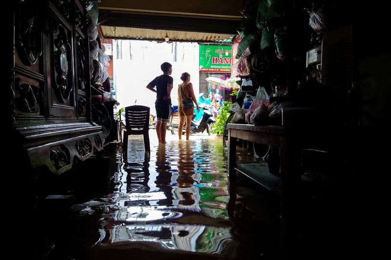 © Reuters. FILE PHOTO: Shop owners stand inside their flooded shop following the impact of Typhoon Yagi, in Hanoi, Vietnam, September 11, 2024. REUTERS/Khanh Vu/File Photo