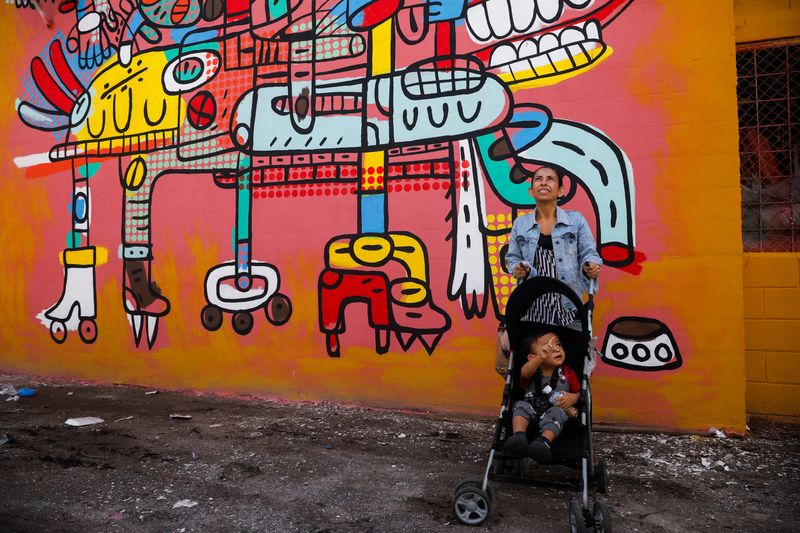 © Reuters. A woman stands by a mural titled 