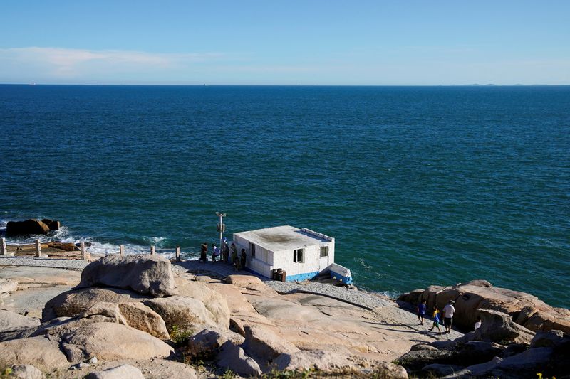 © Reuters. FILE PHOTO: People stand near a building overlooking the Taiwan Strait, at the 68-nautical-mile scenic spot, one of mainland China's closest points to the island of Taiwan, in Pingtan island, Fujian province, China August 5, 2022. REUTERS/Aly Song/File Photo