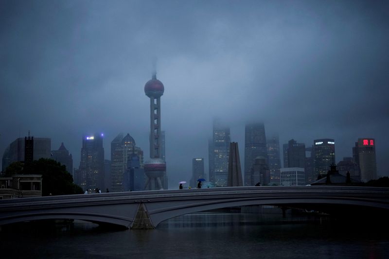 © Reuters. FILE PHOTO: People walk with umbrellas on a bridge amid rains and winds brought by Typhoon Muifa, in Shanghai, China September 14, 2022. REUTERS/Aly Song/File Photo