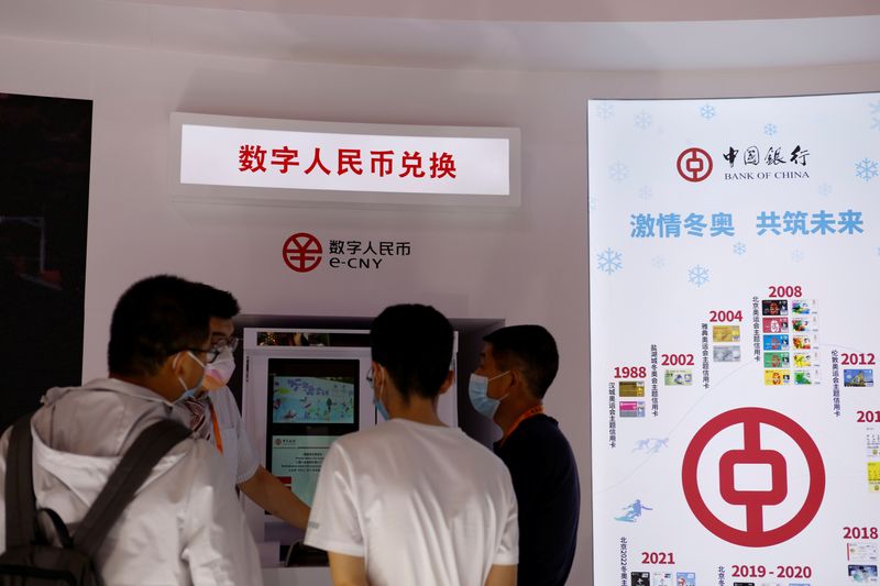 © Reuters. FILE PHOTO: A staff member tends to visitors at an automated teller machine (ATM) offering services for China's digital yuan, or e-CNY, at the Bank of China booth during the China International Fair for Trade in Services (CIFTIS) of 2021 in Beijing, China September 4, 2021. REUTERS/Florence Lo/File Photo