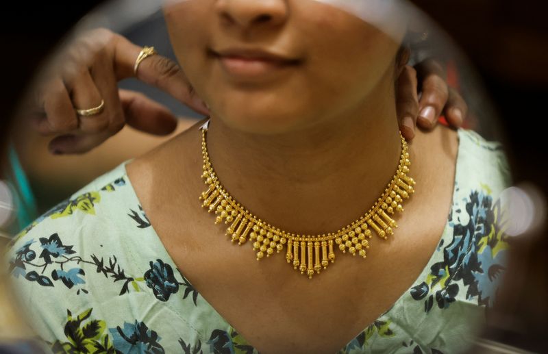 © Reuters. FILE PHOTO: A woman tries on a gold necklace at a jewellery showroom in Mumbai, India, November 10, 2023. REUTERS/Francis Mascarenhas/File Photo