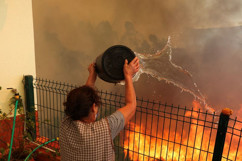 &copy; Reuters. Mulher tenta apagar chamas perto de sua casa com balde em Vilarinho, Portugaln17/09/2024nREUTERS/Pedro Nunes