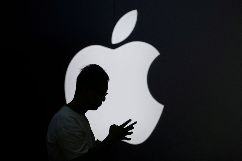 &copy; Reuters. FILE PHOTO: A man checks his phone near an Apple logo outside its store in Shanghai, China September 13, 2023. REUTERS/Aly Song/File Photo