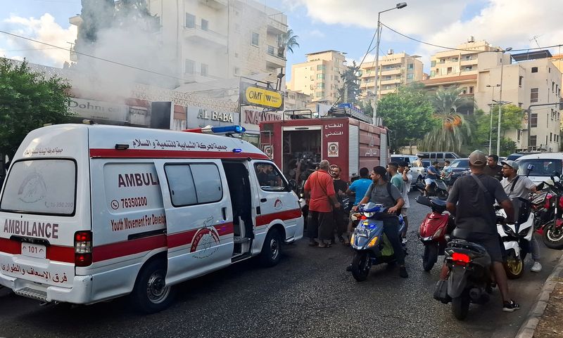 &copy; Reuters. People gather as smoke rises from a mobile shop in Sidon, Lebanon September 18, 2024. REUTERS/Hassan Hankir