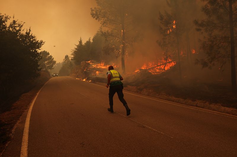 &copy; Reuters. Policial corre em rua cercada por incêndio florestal em São Pedro do Sul, em Portugaln18/09/2024nREUTERS/Pedro Nunes