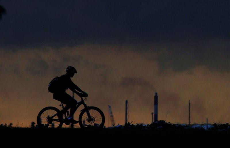 &copy; Reuters. FILE PHOTO: A man cycles past a chimney giving off emissions in an industrial area of Singapore January 5, 2016. REUTERS/Tim Wimborne/File Photo