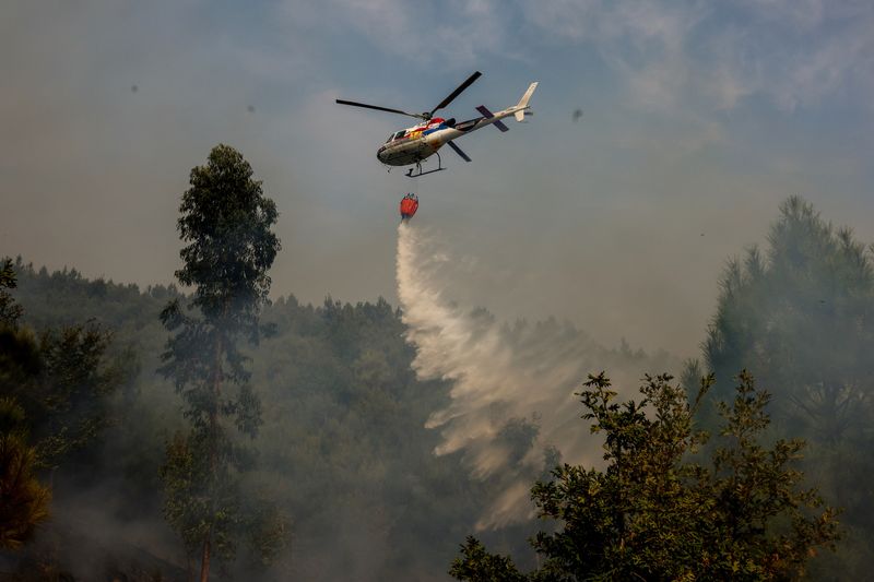 &copy; Reuters. A helicopter drops water on a terrain during a wildfire in Castro Daire, Portugal, September 19, 2024. REUTERS/Pedro Nunes