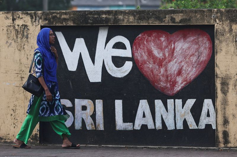 © Reuters. A woman walks past graffiti on a wall along a main road, ahead of the upcoming presidential election scheduled for September 21, in Colombo, Sri Lanka September 19, 2024. REUTERS/Dinuka Liyanawatte