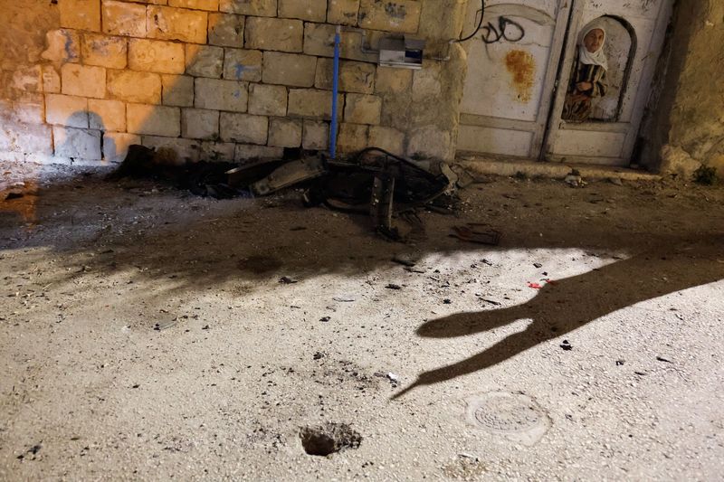 © Reuters. A Palestinian woman looks on, near the site of an Israeli airstrike on a car, in Qabatya, near Jenin, in the Israeli-occupied West Bank, September 19, 2024. REUTERS/Raneen Sawafta