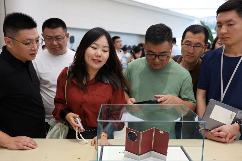 © Reuters. FILE PHOTO: People look at Huawei's new tri-foldable smartphone Mate XT displayed in a glass case at a Huawei flagship store in Beijing, China September 10, 2024. REUTERS/Florence Lo/File Photo