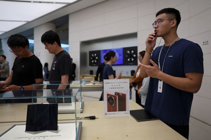 © Reuters. A staff member introduces Huawei Mate XT as the tri-foldable smartphone goes on sale at a Huawei flagship store in Beijing, China September 20, 2024. REUTERS/Florence Lo