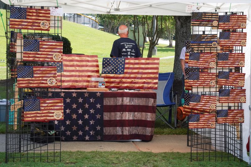 &copy; Reuters. A man with a stand selling wooden American flags turns around at the Pigs and Peaches country festival in Kennesaw, Georgia, U.S. August 17, 2024.  REUTERS/Megan Varner/File Photo