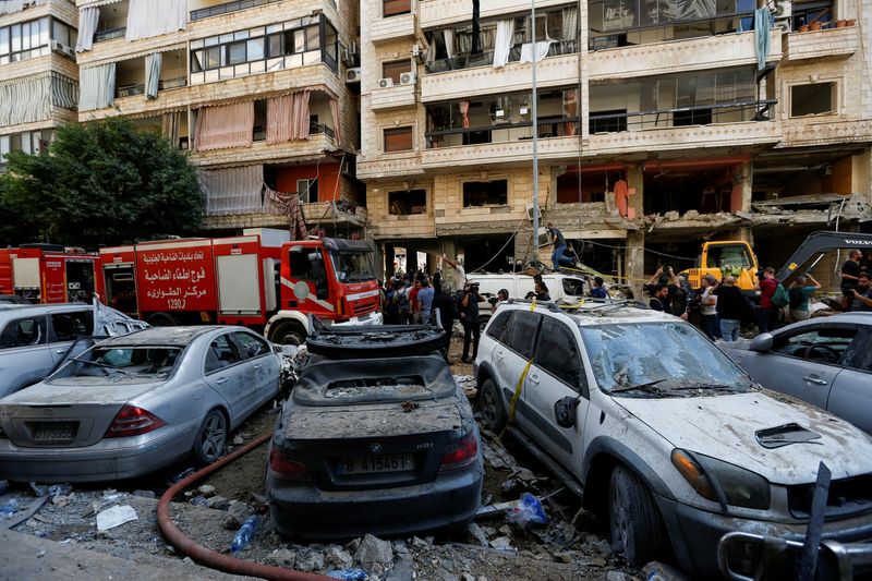 © Reuters. People gather near a firetruck and damaged vehicles at the site of Friday's Israeli strike, as search and rescue operations continue, in Beirut's southern suburbs, Lebanon September 21, 2024. REUTERS/Amr Abdallah Dalsh