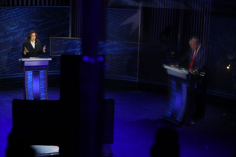 © Reuters. FILE PHOTO: Democratic presidential nominee, U.S. Vice President Kamala Harris speaks during a presidential debate hosted by ABC as Republican presidential nominee, former U.S. President Donald Trump is reflected on a panel as he listens, in Philadelphia, Pennsylvania, U.S., September 10, 2024. REUTERS/Brian Snyder/File Photo