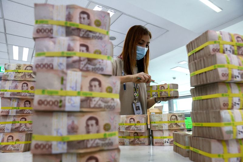 © Reuters. FILE PHOTO: A bank employee gathers Thai baht notes at a Kasikornbank in Bangkok, Thailand, January 26, 2023. REUTERS/Athit Perawongmetha/File Photo