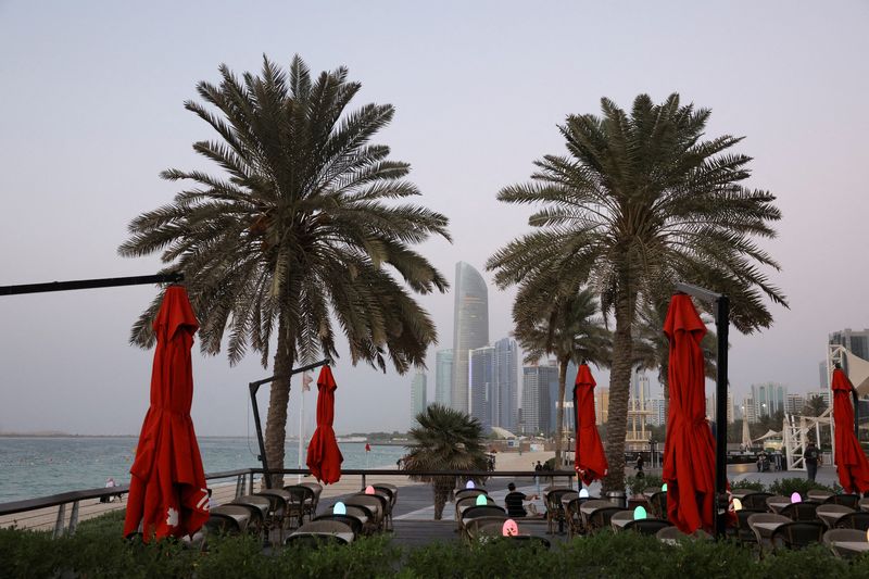 &copy; Reuters. FILE PHOTO: People relax near palm trees as the skyline is seen in the background in Abu Dhabi, United Arab Emirates, September 27, 2023. REUTERS/Amr Alfiky/File Photo