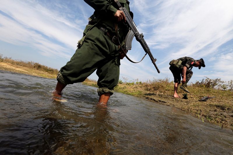 © Reuters. FILE PHOTO: A soldier from the Kachin Independence Army (KIA) puts on his shoes as he and his comrade cross a stream towards the front line in Laiza, Kachin state, January 29, 2013. REUTERS/David Johnson/File Photo