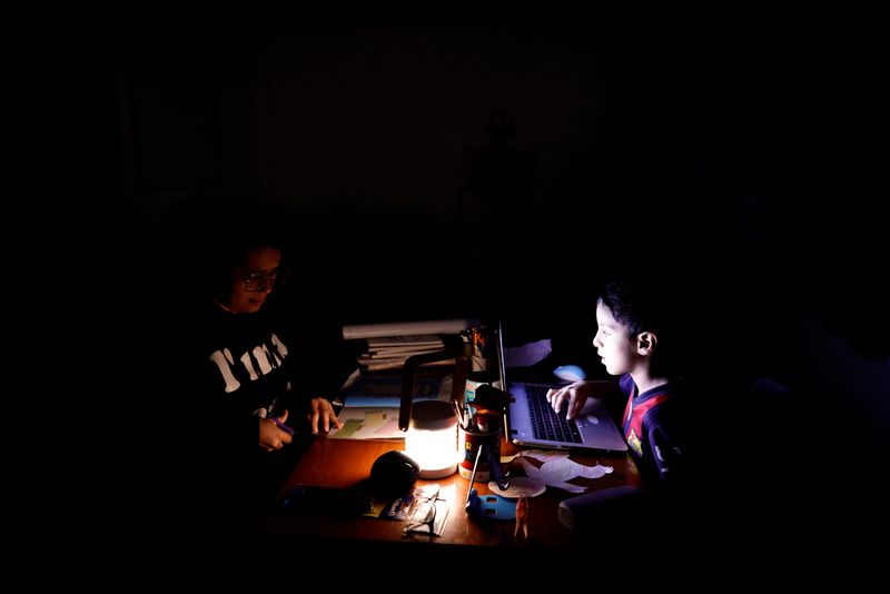 © Reuters. Esther Gualtieri and her son Rafael Diaz Gualtieri do school-work during a power outage, in Quito, Ecuador September 23, 2024. REUTERS/Karen Toro