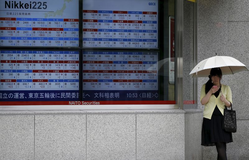 &copy; Reuters. Una donna guarda il suo cellulare accanto a un tabellone di quotazioni azionarie fuori da un broker a Tokyo, 30 giugno 2015. La media azionaria giapponese Nikkei è rimbalzata martedì dopo aver registrato il secondo maggior calo giornaliero di quest'anno