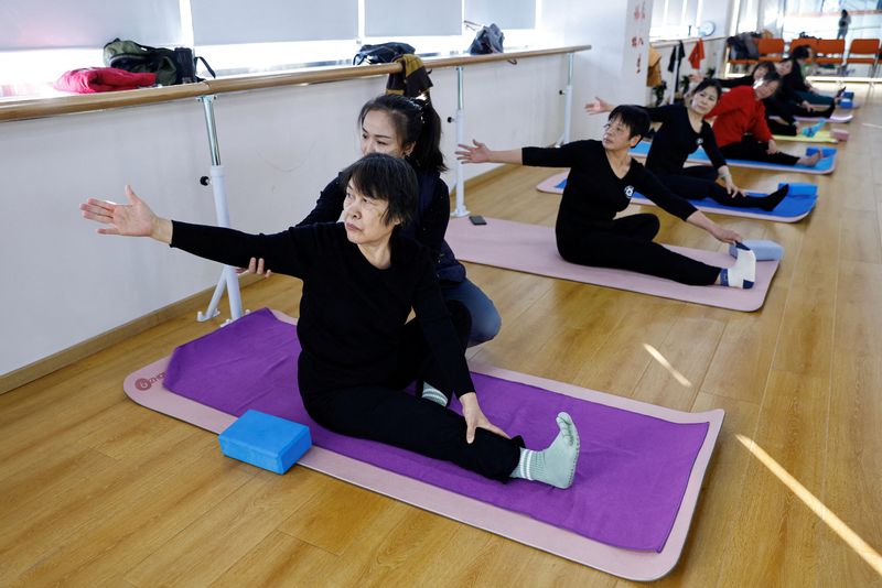 &copy; Reuters. FILE PHOTO: A teacher coaches an elderly person during a yoga class at Mama Sunset, a learning centre for middle-aged and senior people in Beijing, China January 15, 2024. REUTERS/Tingshu Wang/File Photo