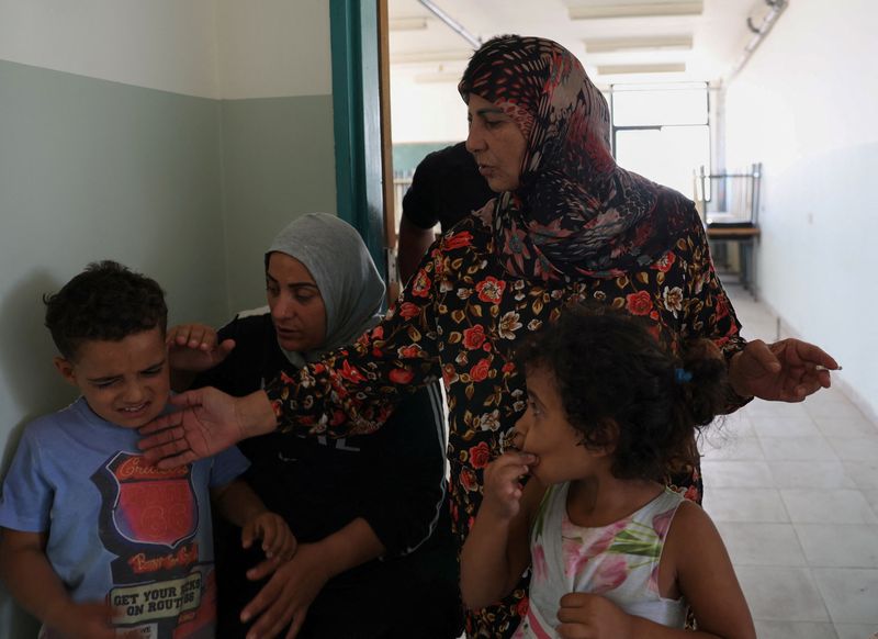 © Reuters. Feryal Mehsen, 58, who fled from southern Lebanon due to ongoing cross-border hostilities between Hezbollah and Israeli forces, stands with her family members in a hallway, at the Technical Institute of Bir Hassan turned into a shelter in Beirut, Lebanon September 24, 2024. REUTERS/Emilie Madi