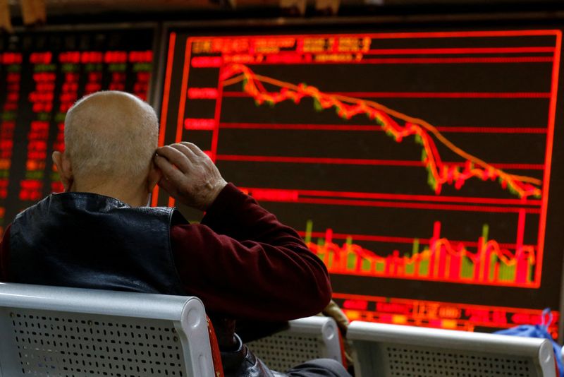 © Reuters. FILE PHOTO: An investor stands in front of a board showing stock information at a brokerage office in Beijing, China, December 7, 2018. REUTERS/Thomas Peter/File Photo