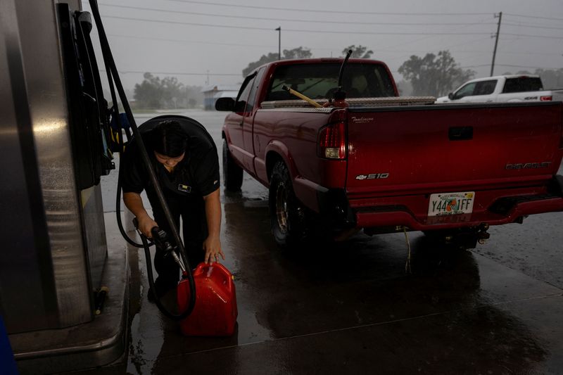 © Reuters. A woman fills up a container with gas as Hurricane Helene intensifies before its expected landfall on Florida’s Big Bend, in Cross City, Florida, U.S. September 25, 2024.  REUTERS/Marco Bello