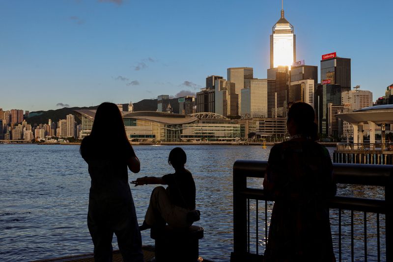 &copy; Reuters. FILE PHOTO: Tourists relax by the Victoria Harbour waterfront, with the iconic skyline providing a scenic backdrop, in Hong Kong, China, July 10, 2023. REUTERS/Tyrone Siu/File Photo